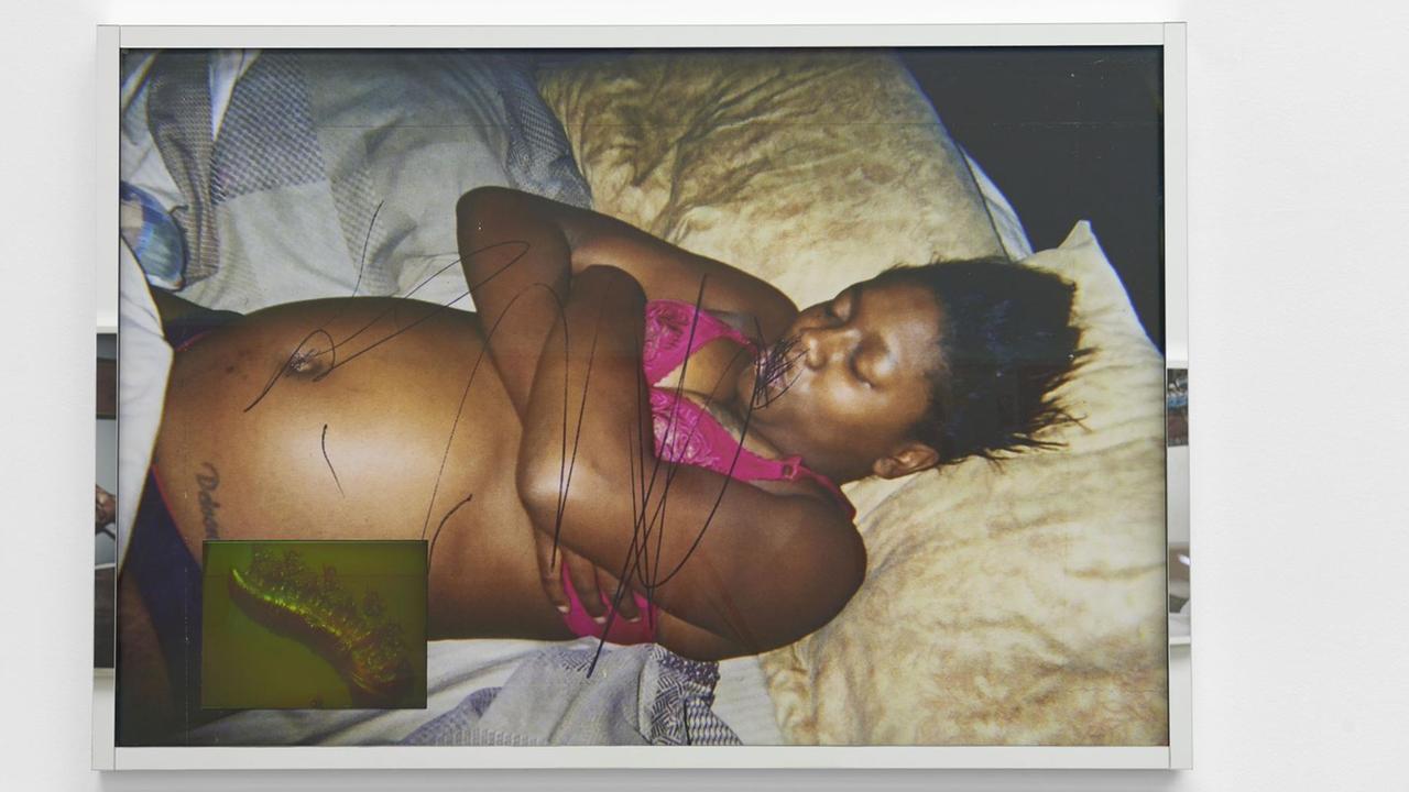 Das Bild zeigt die Fotografie einer Afroamerikanerin, die halb nackt im Bett liegt.