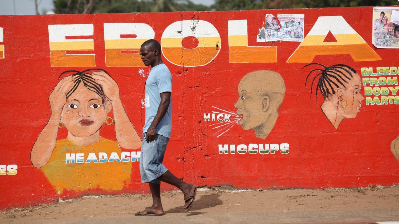 Ein Mann geht in Liberias Hauptstadt Monrovia an einer roten Wandmalerei vorbei, die vor dem Ebola-Virus warnt