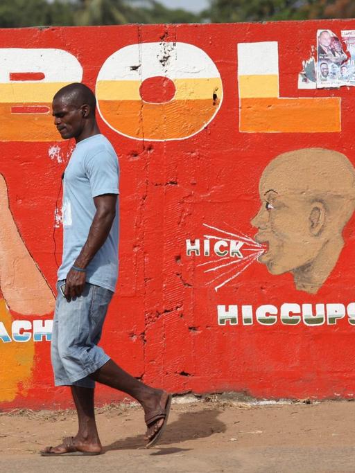 Ein Mann geht in Liberias Hauptstadt Monrovia an einer roten Wandmalerei vorbei, die vor dem Ebola-Virus warnt