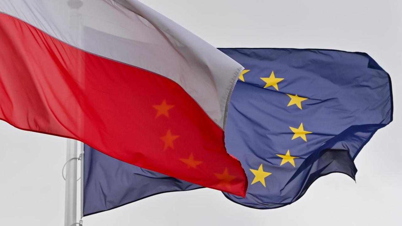 Die weiß-rote Nationalfahne Polens und dahinter die Fahne der Europäischen Union (EU) wehen im Wind Die weiß-rote Nationalfahne Polens und dahinter die Fahne der Europäischen Union (EU) wehen im Wind