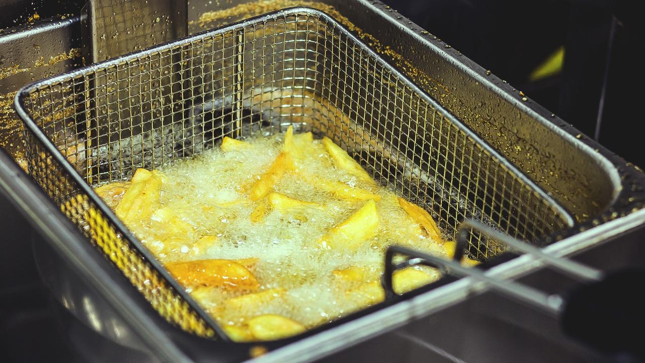 In einer Fritteuse werden in heißem Fett Pommes zubereitet.