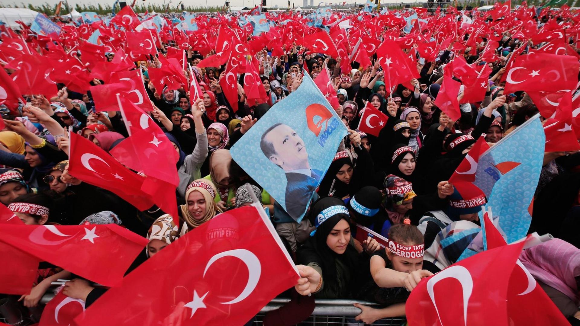 Unterstützer der regierenden AKP schwenken die Flagge der Türkei und halten ein Bild Erdogans hoch.