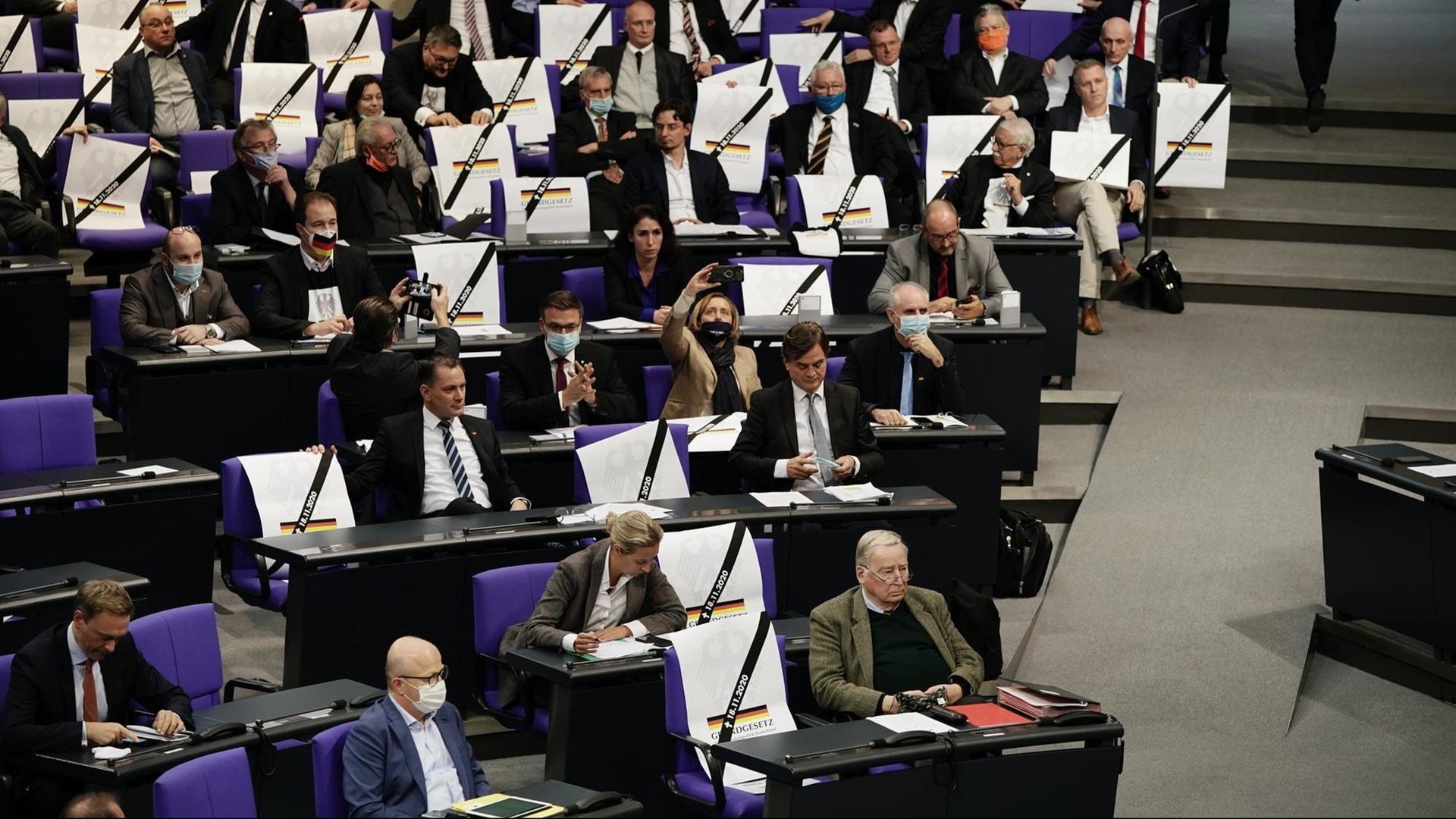 Die AfD-Fraktion im Bundestag hat Plakate auf leere Sitze zwischen ihre Abgeordneten gestellt, stilisiert als vermeintliche Todesanzeigen für das Grundgesetz.