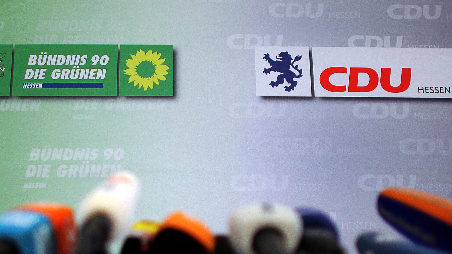 Im Vordergrund sind unscharf ein Dutzend Mikrofone zu erkennen, dahinter die Logos der Gründen und der CDU.
