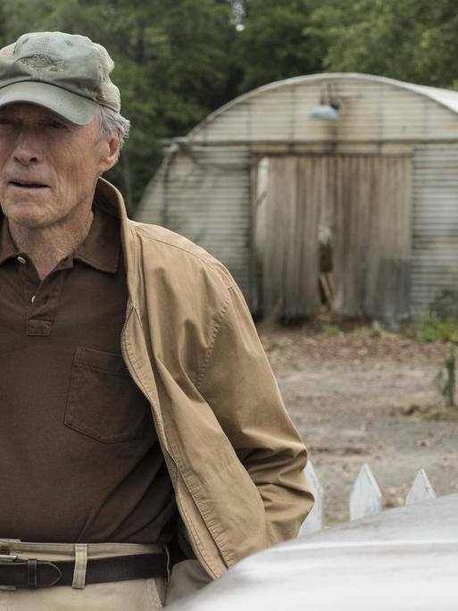 Das von der Filmfirma Warner Bros. Pictures veröffentlichte Bild zeigt Clint Eastwood in einer Szene in "The Mule". Er hat eine Schirmmütze auf, im Hintergrund sind Gewächshäuser zu sehen.
