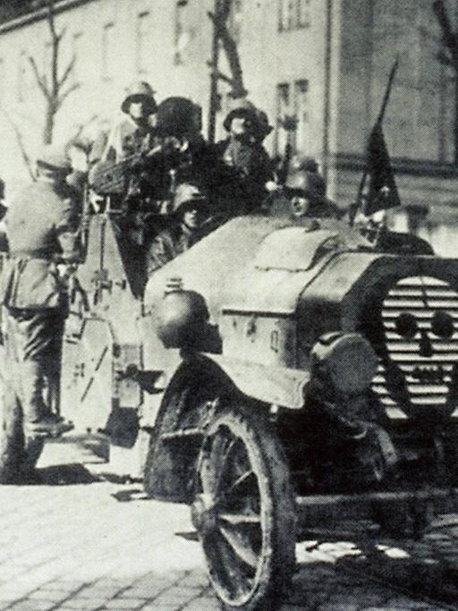 Eine Gruppe Männer in einem Wagen mit Totenkopf Symbol fahren als Freikorps auf den Straßen in Berlin in den 1920er Jahren.