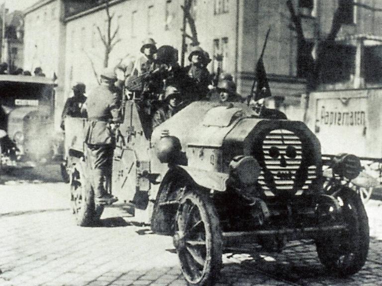 Eine Gruppe Männer in einem Wagen mit Totenkopf Symbol fahren als Freikorps auf den Straßen in Berlin in den 1920er Jahren.