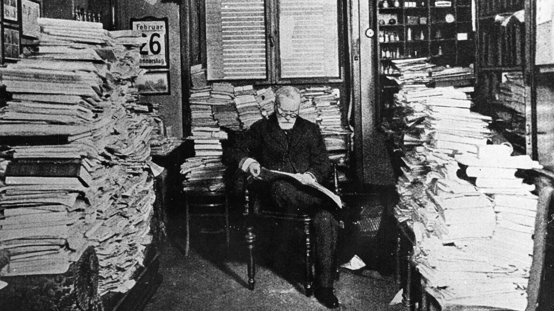 Der deutsche Arzt und Forscher Paul Ehrlich sitzt zwischen riesigen Stapeln Papier.