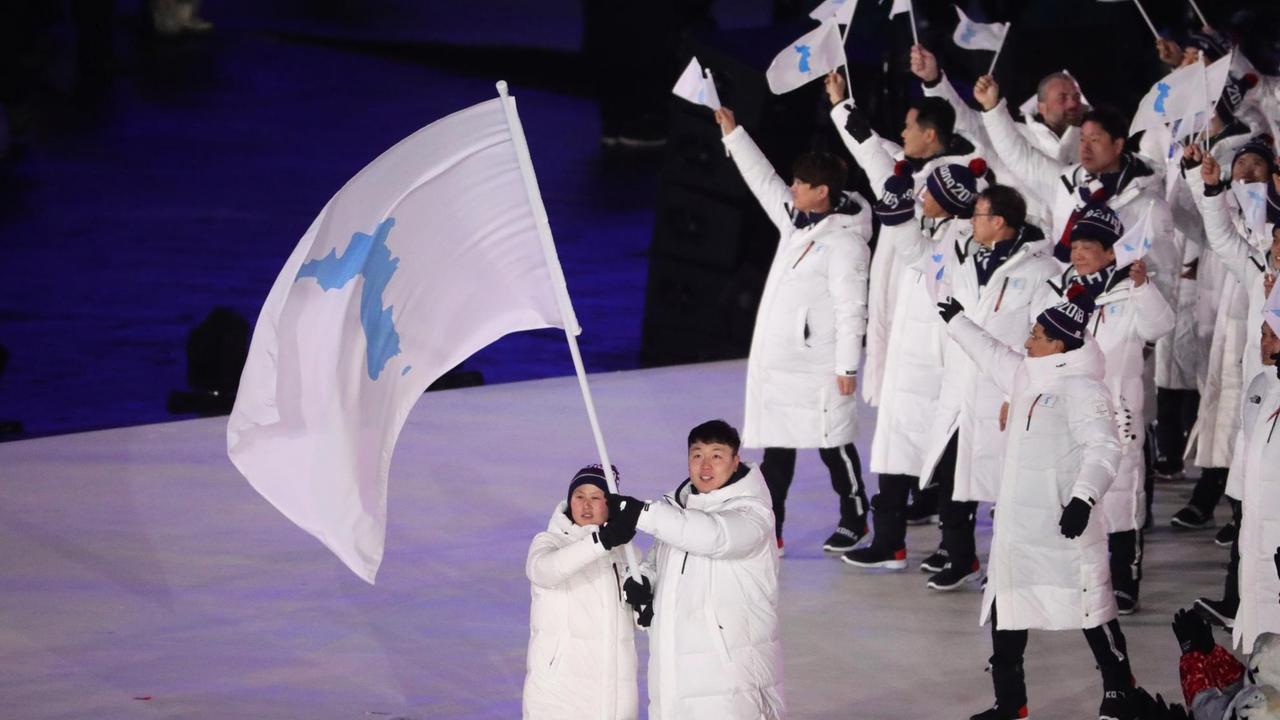 Won Yun Jong, Bobfahrer aus Südkorea, und Hwang Chung Gum, Eishockeyspielerin aus Nordkorea, halten bei der Eröffung der Olympischen Winterspiele 2018 in Pyeongchang gemeinsam eine Fahne mit den Umrissen eines geeinten Koreas