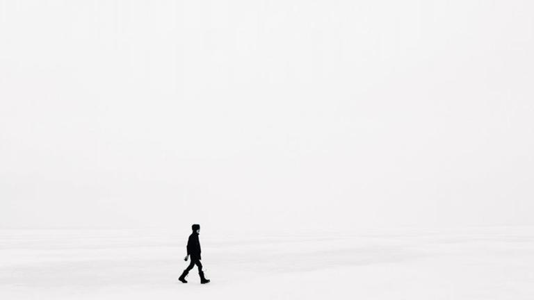 Eine Person läuft in weißem Nebel über Schnee