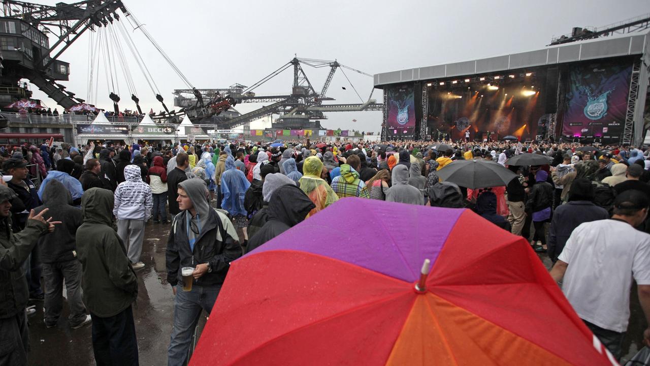 Besucher des HipHop- und Reggae-Festivals "Splash!" stehen am Samstag (11.07.2009) im Regen in der Baggersstadt Ferropolis.