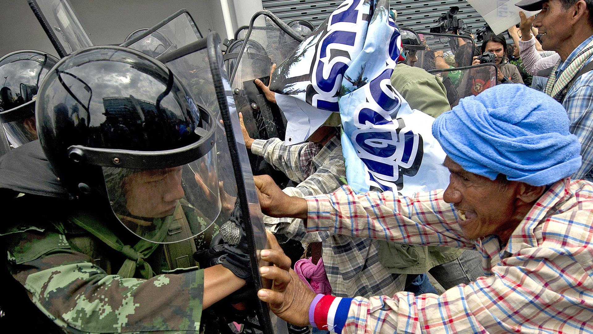 Ein Demonstrant und ein Polizist kämpfen in Thailands Hauptstadt Bangkok gegeneinander.
