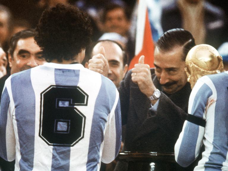Der argentinische Junta-Chef, General Jorge Videla (2.v.r.), freut sich. Er überreicht bei der Siegerehrung am 25.06.1978 im River Plate-Stadion in Buenos Aires den WM-Pokal an Argentiniens Kapitän Daniel Passarella (r), der von seinem Teamgefährten Americo Gallego (Nr. 6) flankiert wird.