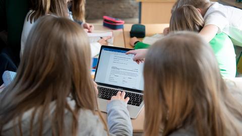 Schüler einer fünften Klasse eines Gymnasiums benutzen im Unterricht einen Laptop