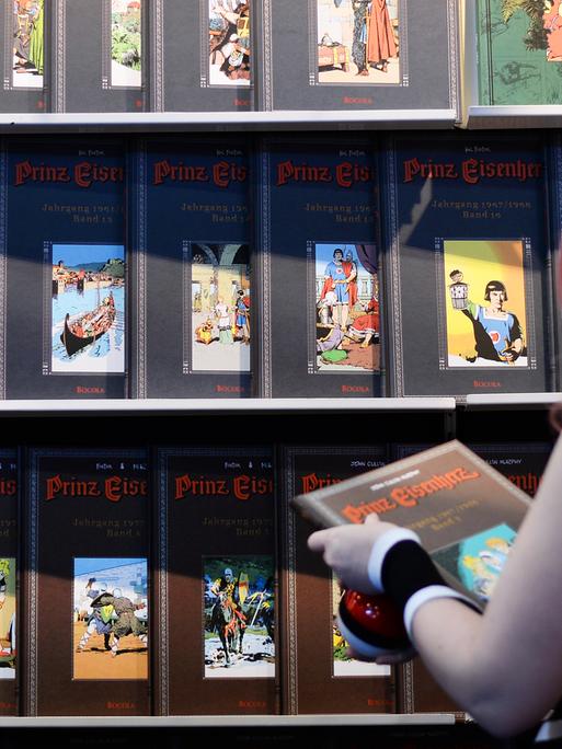 Eine Cosplayerin schaut sich 2017 auf der Buchmesse in Leipzig an einem Stand neue Comics und Bücher an.