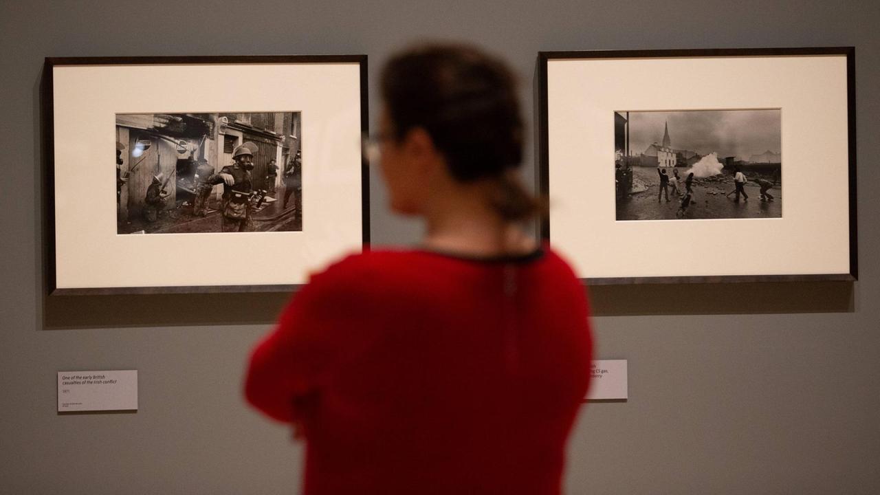 Eine Besucherin schaut sich zwei schwarz-weiß Fotos an der Wand an. 