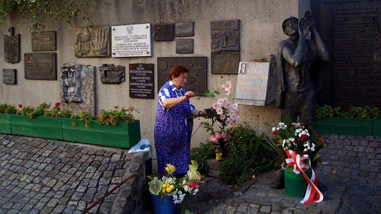 Eine Frau wechselt Blumen am Denkmal des ermordeten Priesters Jerzy Popieluszko vor der ehemaligen Lenin-Werft in Gdansk.