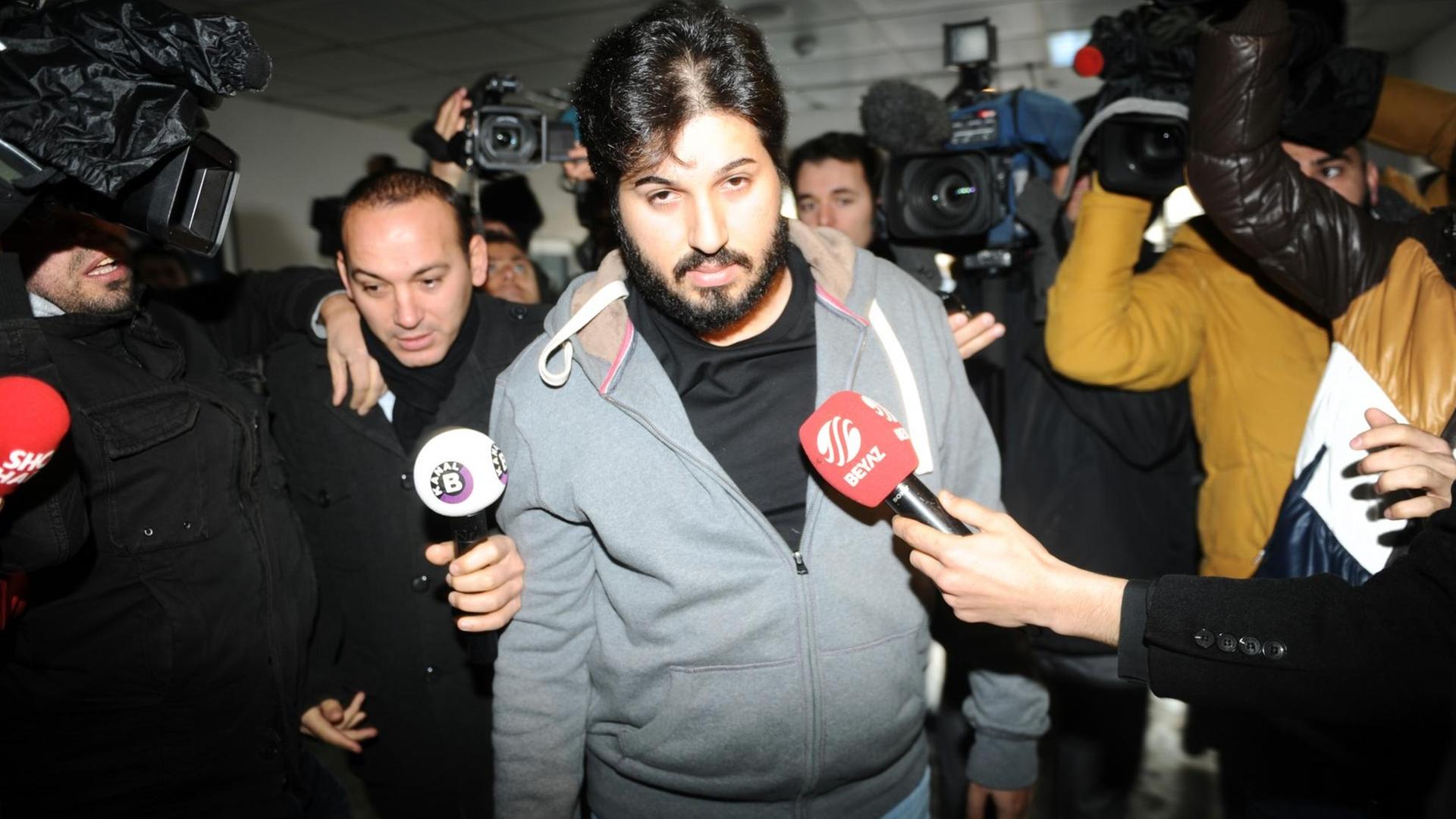 Detained Azerbaijani businessman Reza Zarrab (C) is surrounded by journalists as he arrives at a police center in Istanbul on December 17 ,2013. Turkish police detained more than 20 people including the sons of three cabinet ministers and several high-profile businessmen on December 17 in a probe into alleged bribery and corruption, local media reported. Prime Minister Recep Tayyip Erdogan's ruling Justice and Development Party (AKP), which boasts of being pro-business, has pledged to root out corruption, a chronic problem in Turkey.