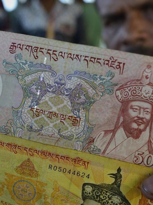 Ein indischer Händler im Bundesland Assam zeigt Geldscheine aus Bhutan.