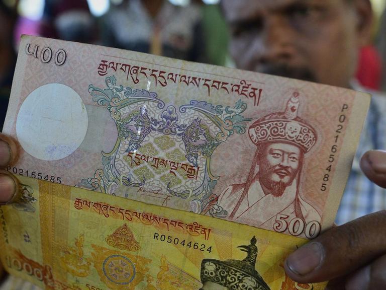 Ein indischer Händler im Bundesland Assam zeigt Geldscheine aus Bhutan.