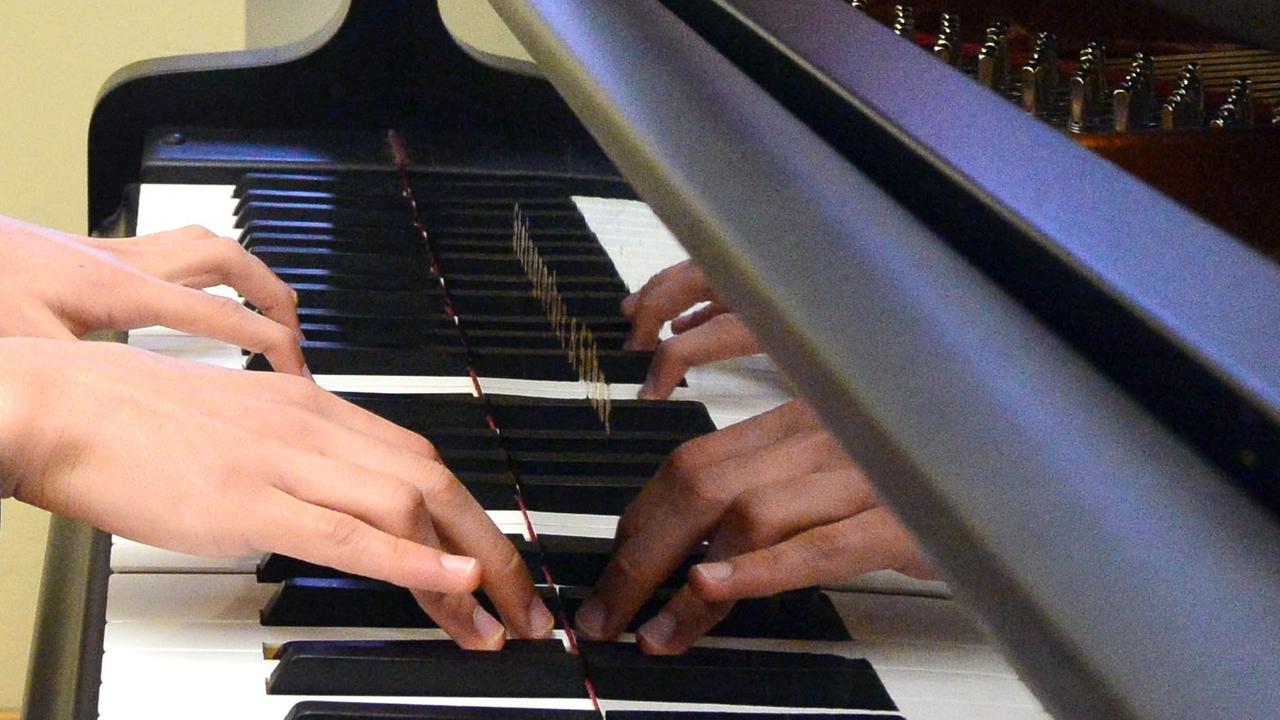 Hände spielen auf einem Klavier.