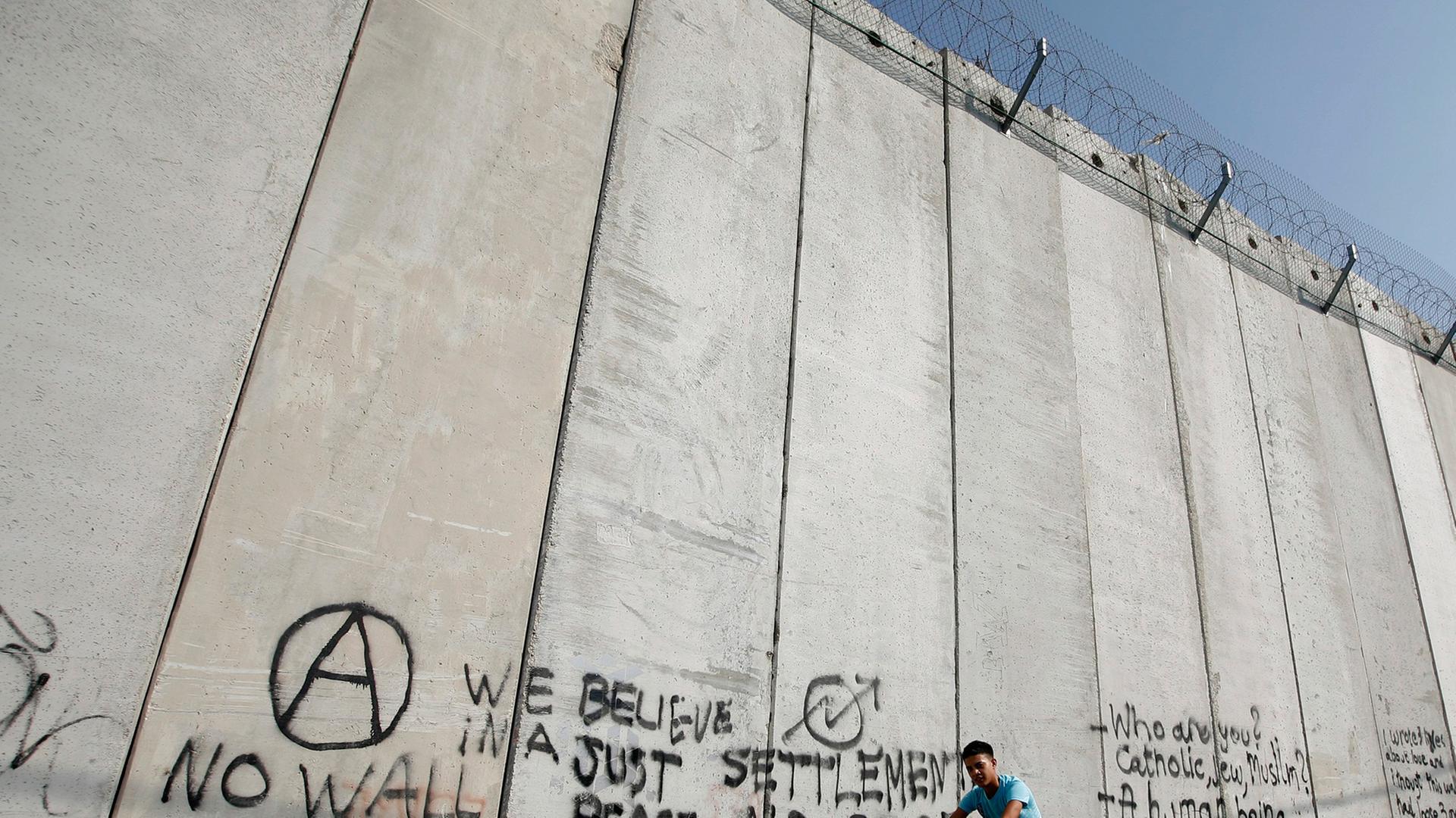 Ein arabischer Junge fährt im Osten Jerusalems auf einem Rad am Trennwall zwischen Israel und dem palästinensischen Gebiet entlang.