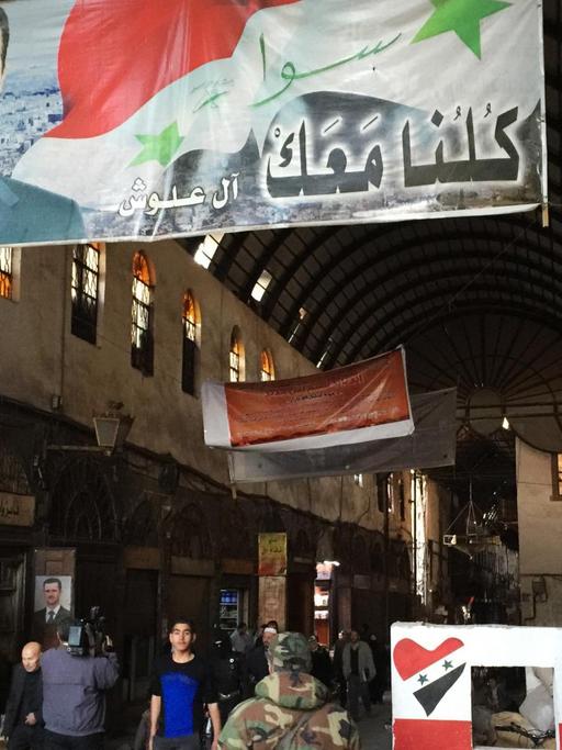 Auf einem Markt in der Altstadt von Damaskus hängt ein Plakat von Baschar al-Assad.