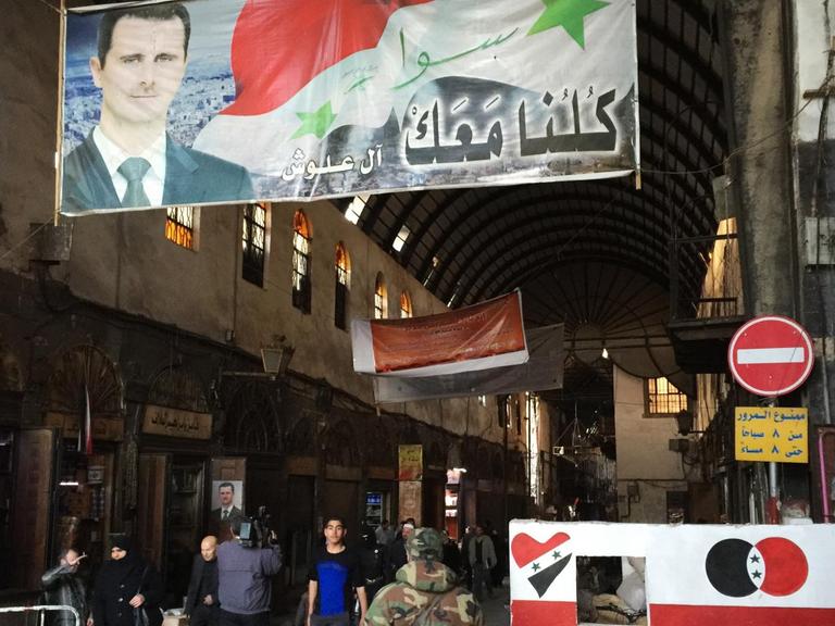 Auf einem Markt in der Altstadt von Damaskus hängt ein Plakat von Baschar al-Assad.