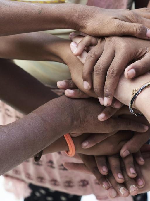Menschen verschiedener Hautfarbe legen ihre Hände übereinander