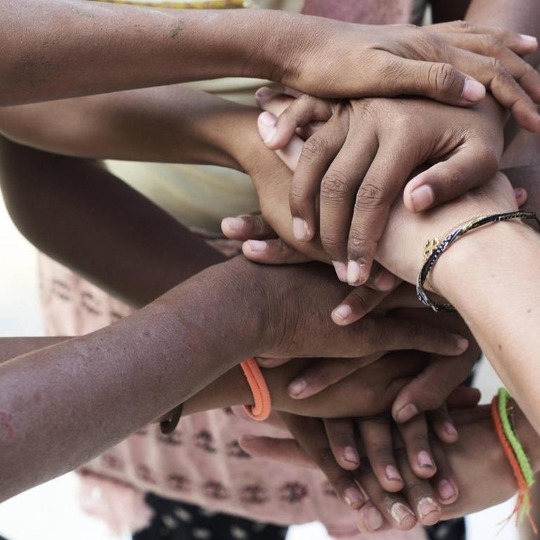 Menschen verschiedener Hautfarbe legen ihre Hände übereinander