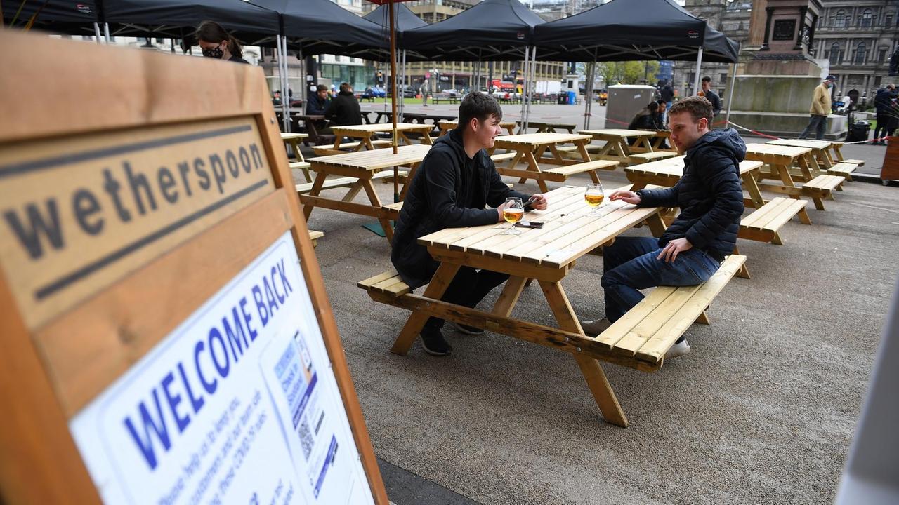 In Schottland dürfen Pubs, Cafés und Restaurants wieder öffnen. Zwei Personen sitzen im Außenbereich eines Pubs.