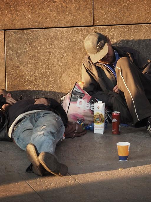 Zwei Obdachlose liegen auf einem Fußweg an einer Hauptstraße im Bezirk Mitte in Berlin am 04.10.2014.