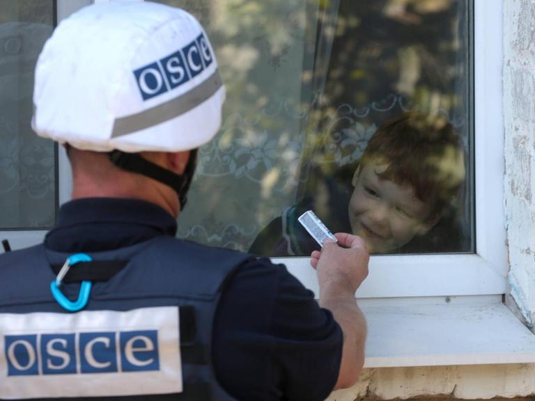 Ein Mitarbeiter der OSZE-Beobachtermission in der Ukraine interagiert mit einem Jungen in einem Dorf in der Region Donezk.
