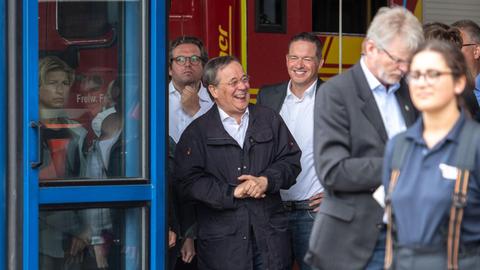 Armin Laschet (2. v.l., CDU), Ministerpräsident von Nordrhein-Westfalen, lacht während Bundespräsident Steinmeier (nicht im Bild) im Hochwassergebiet in Erftstadt ein Pressestatement gibt.
