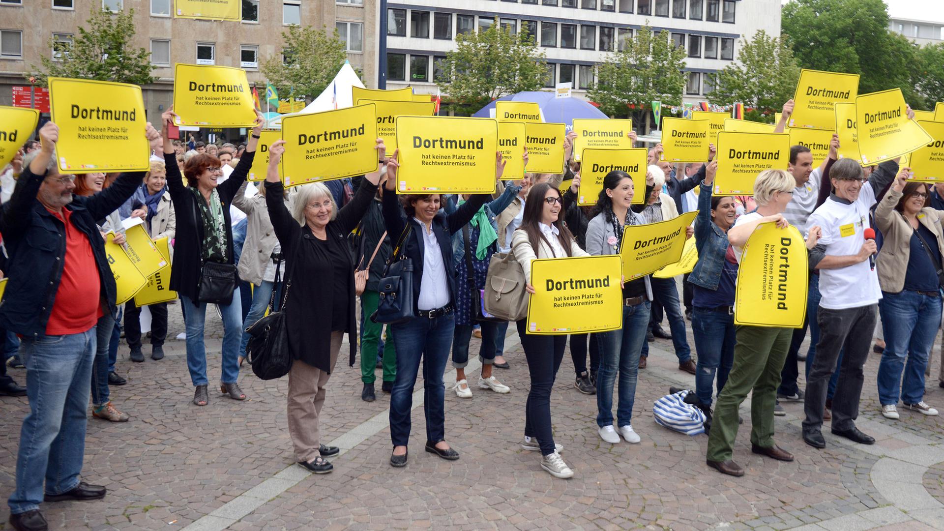 Bürger halten in Dortmund (Nordhein-Westfalen) vor dem Rathaus während einer Demonstration Schilder gegen Rechtsextremismus hoch.