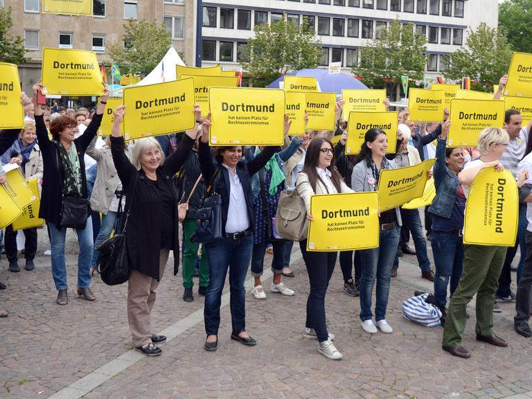 Bürger halten in Dortmund (Nordhein-Westfalen) vor dem Rathaus während einer Demonstration Schilder gegen Rechtsextremismus hoch.