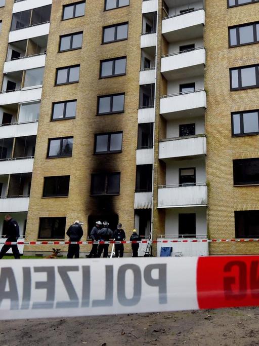 Polizisten stehen am 16.10.2015 in Flensburg vor einer zum Teil ausgebrannten Asylbewerberunterkunft