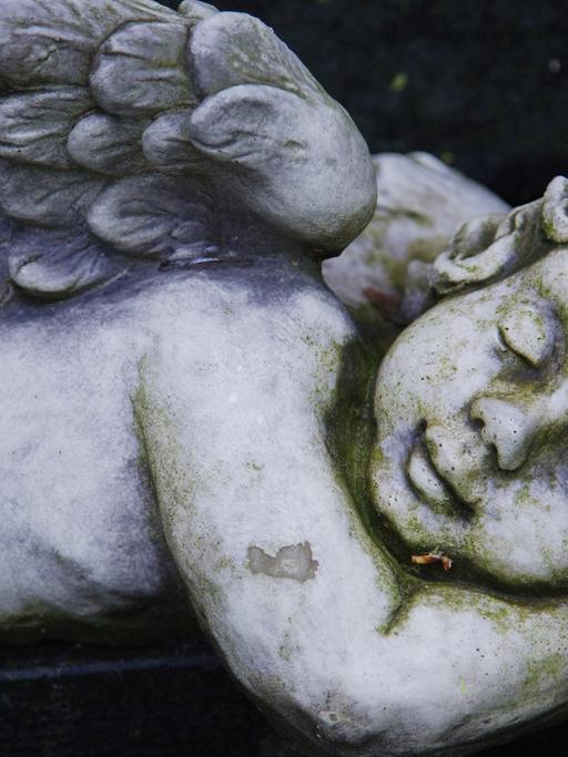 Eine Engel-Skulptur liegt auf einem Grab 