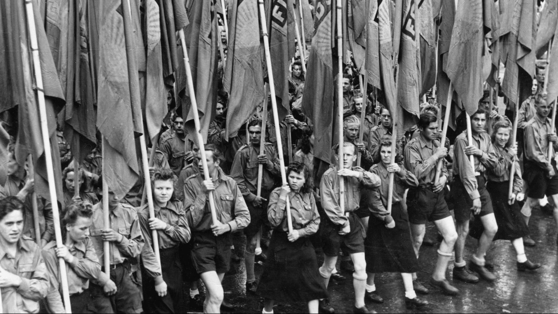 Mitglieder der "Freien Deutschen Jugend" tragen Fahnen der FDJ auf dem Weg zum Lustgarten in Berlin