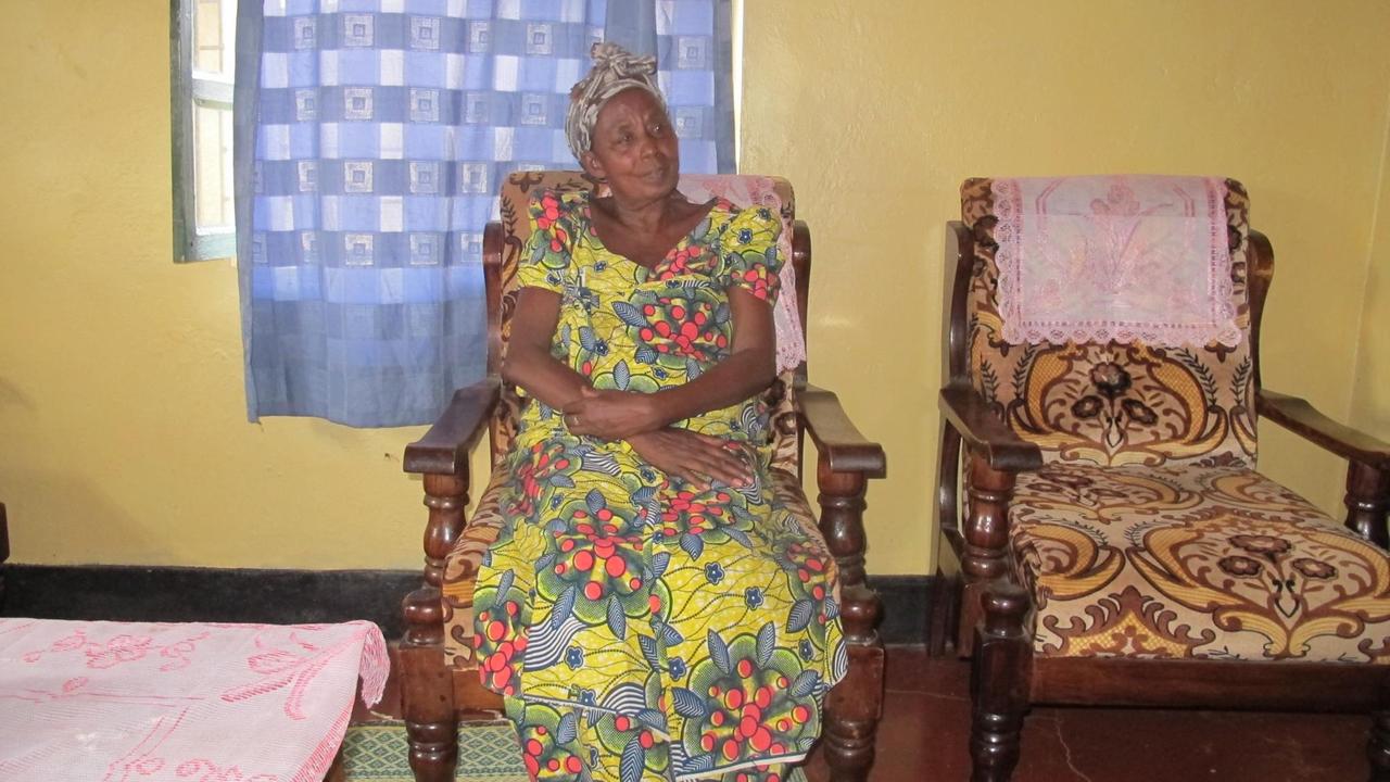 Ältere Frau in afrikanischer Tracht auf Sessel