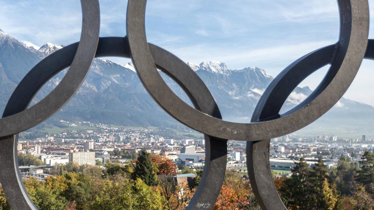 Das Olympische Feuer am Bergisel. Im Vordergrund die olympischen Ringe. Im Hintergrund das Panorama von Innsbruck. 