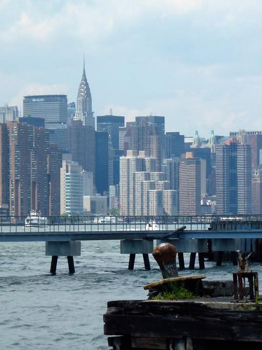 Blick auf den East River mit Manhattan im Hintergrund, aufgenommen vom Ufer in Williamsburg, Brooklyn, New York am 22.06.2014