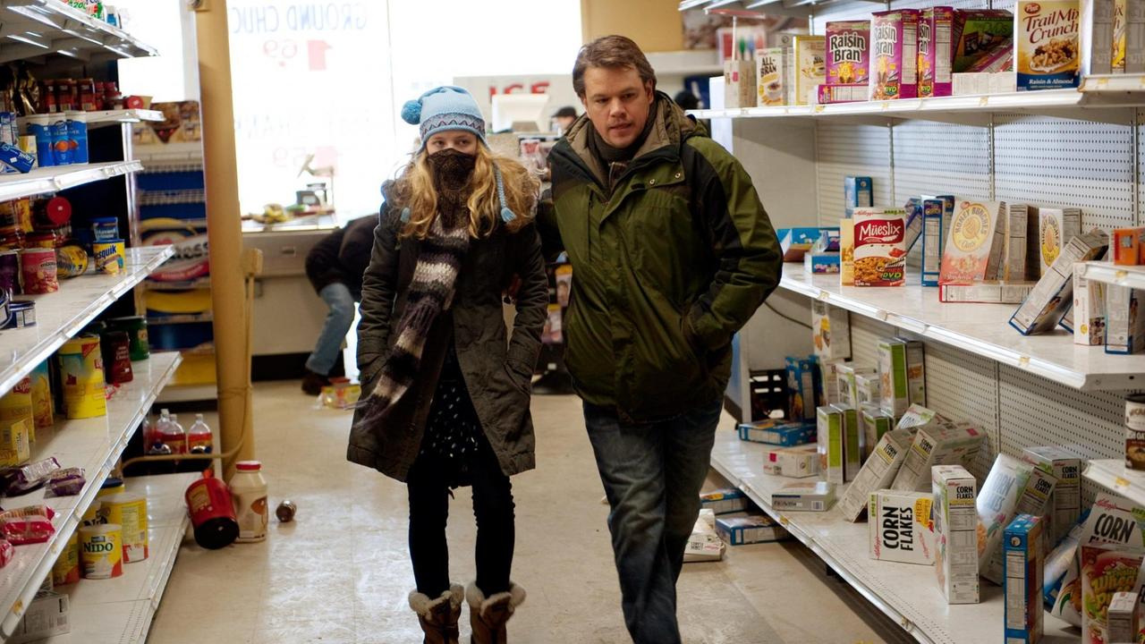 Die Schauspielerin Anna Jacoby-Heron, und der Schauspieler Matt Damon in dem Film "Contagion" von 2011. Eine Frau mit Maske und ein Mann gehen durch einen Supermarkt.