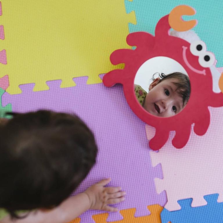 Ein Baby schaut sich im Spielzeugspiegel an