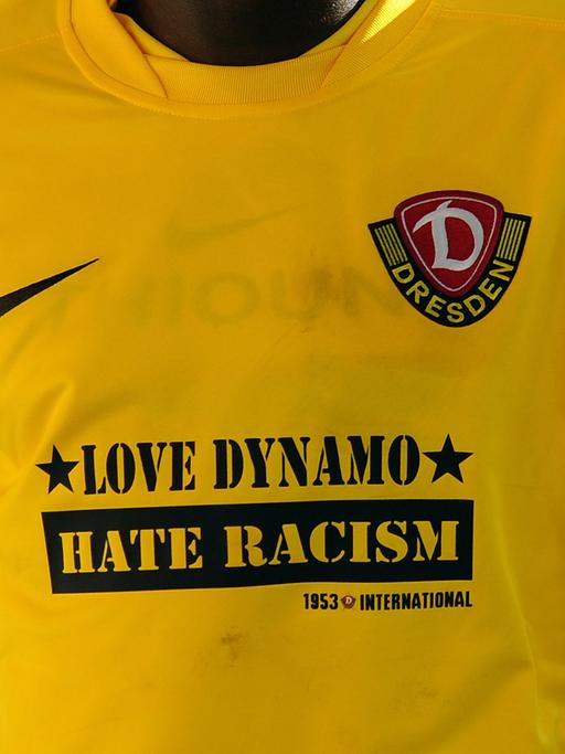 Ein dunkelhäutiger Fußballer trägt ein Trikot vom SG Dynamo Dresden mit dem Slogan "Love Dynamo Hate Racism"