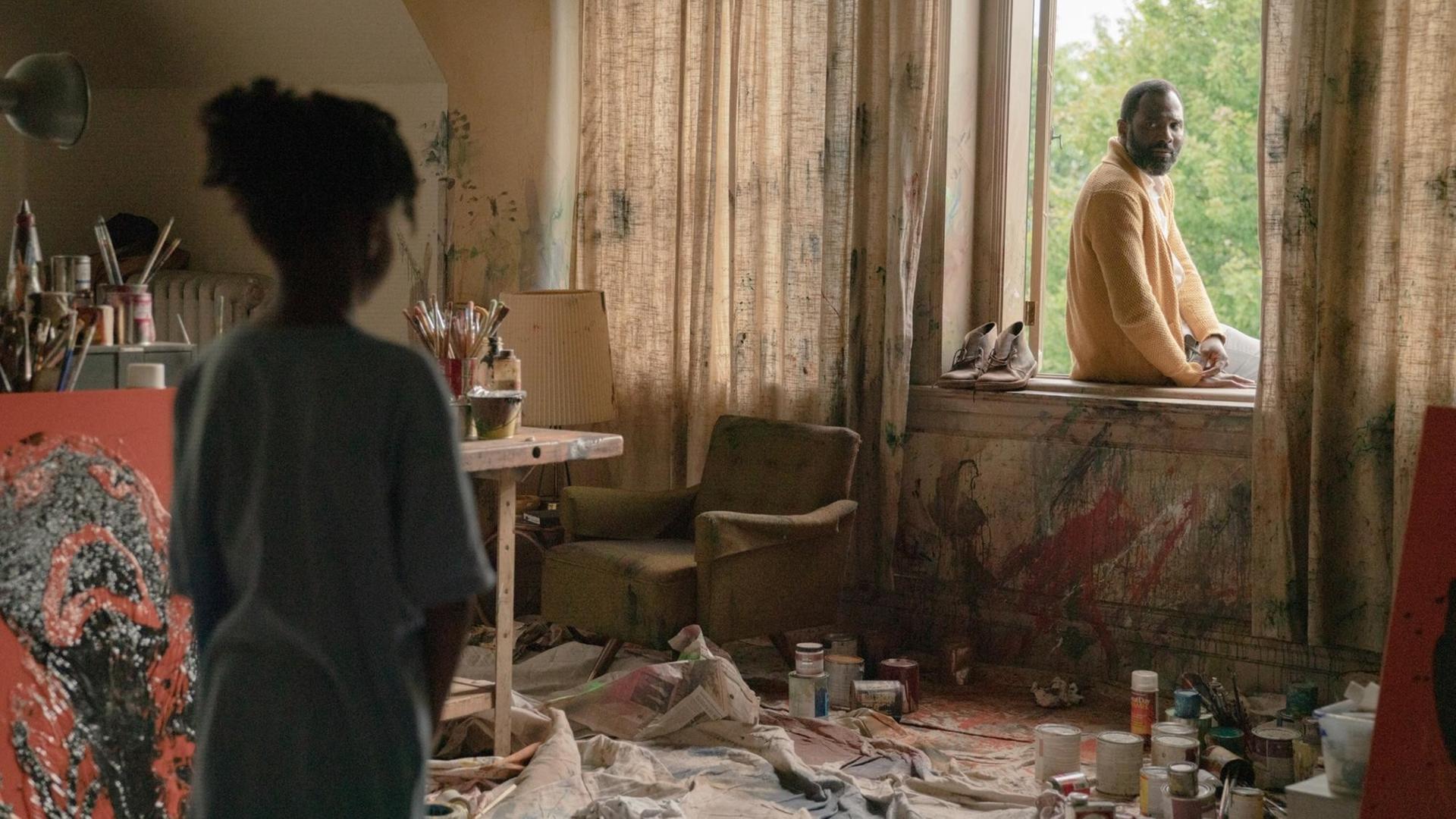 Szene aus dem Film "Candyman": ein verwüstetes Zimmer, links steht ein Mädchen, das zum Fenster blickt, auf dessen Rand ein Mann sitzt und zu ihm schaut. (links: Hannah Love Jones, rechts: Carl Clemons-Hopkins)