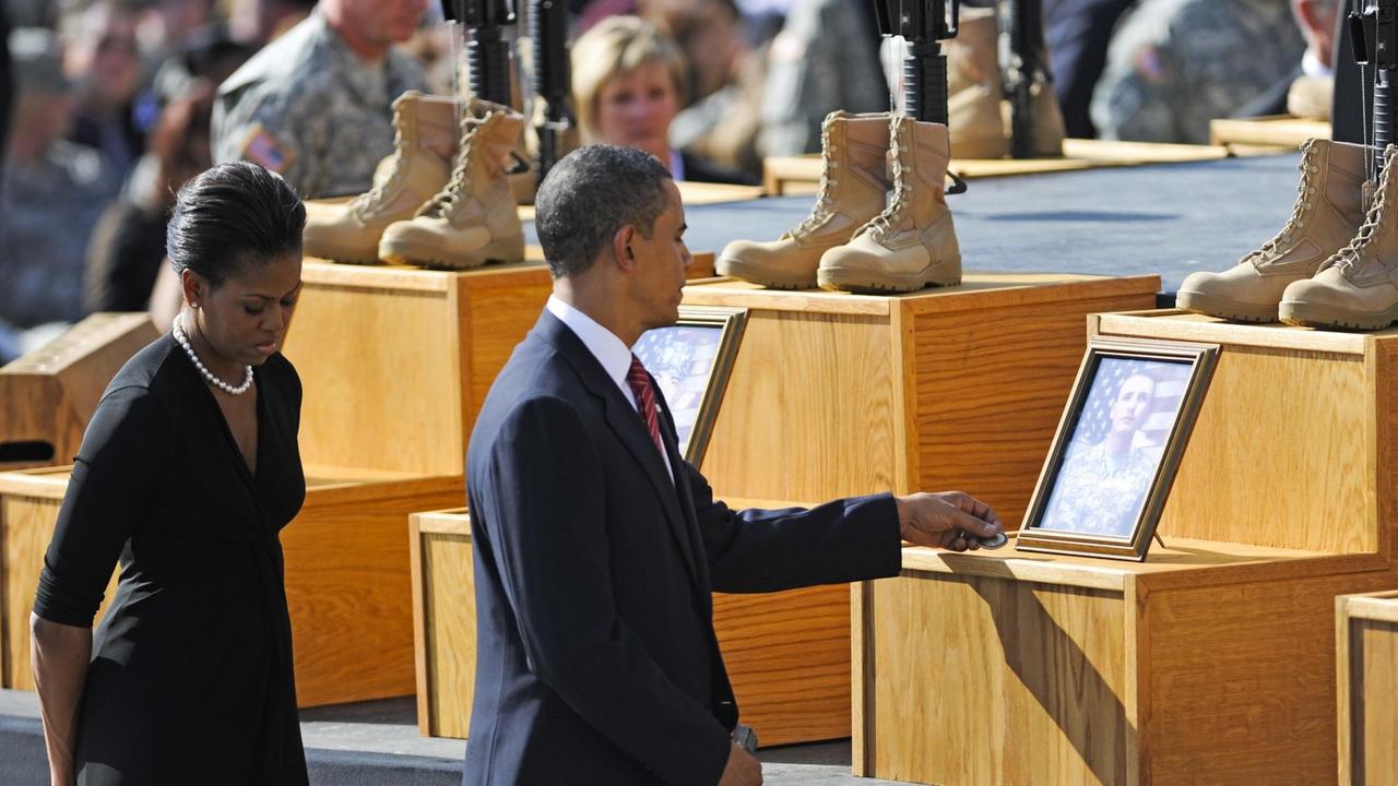 Barack Obama und seine Frau Michelle vor Denkmälern zu Ehren von toten Soldaten.