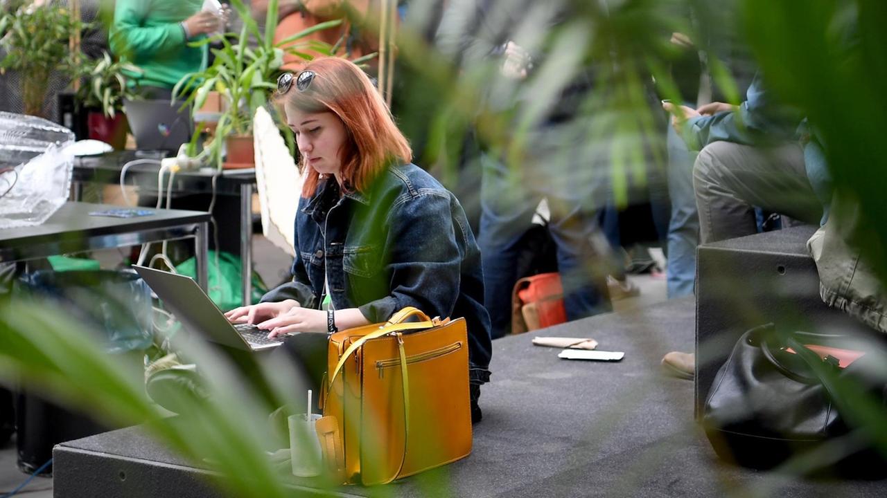 06.05.2019, Berlin: Eine junge Frau sitzt an ihrem Laptop im Community Garden auf dem Gelände Internetkonferenz "re:publica".