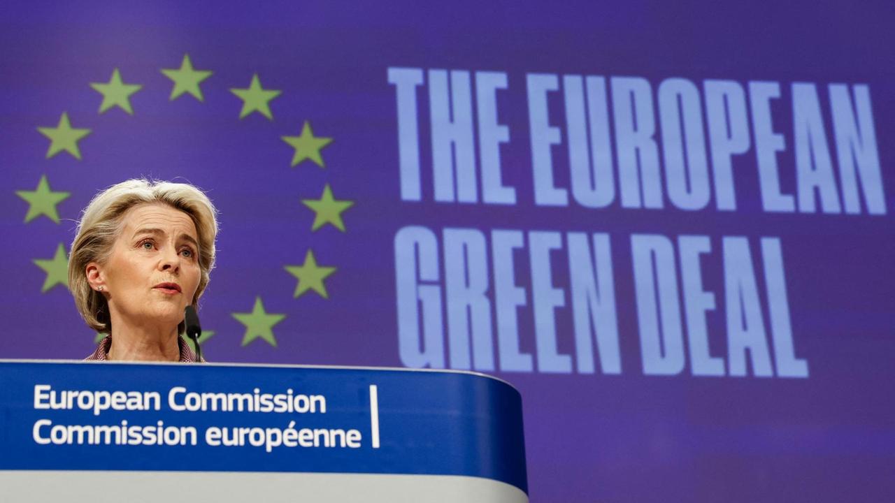 EU-Kommissionspräsidentin von der Leyen sitzt auf einem Podium; im Hintergrund sieht man einen Ring aus Europa-Sternen.