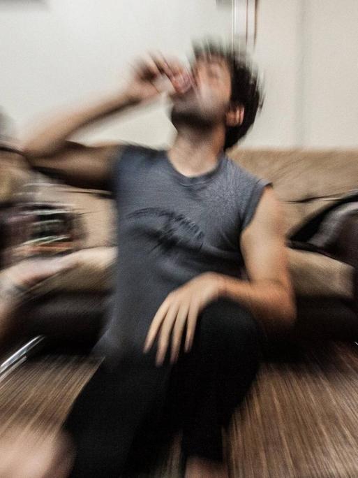 Schemenhaft sind junge Iraner zu sehen, die abends gemeinsam in einer Wohnung Alkohol trinken.